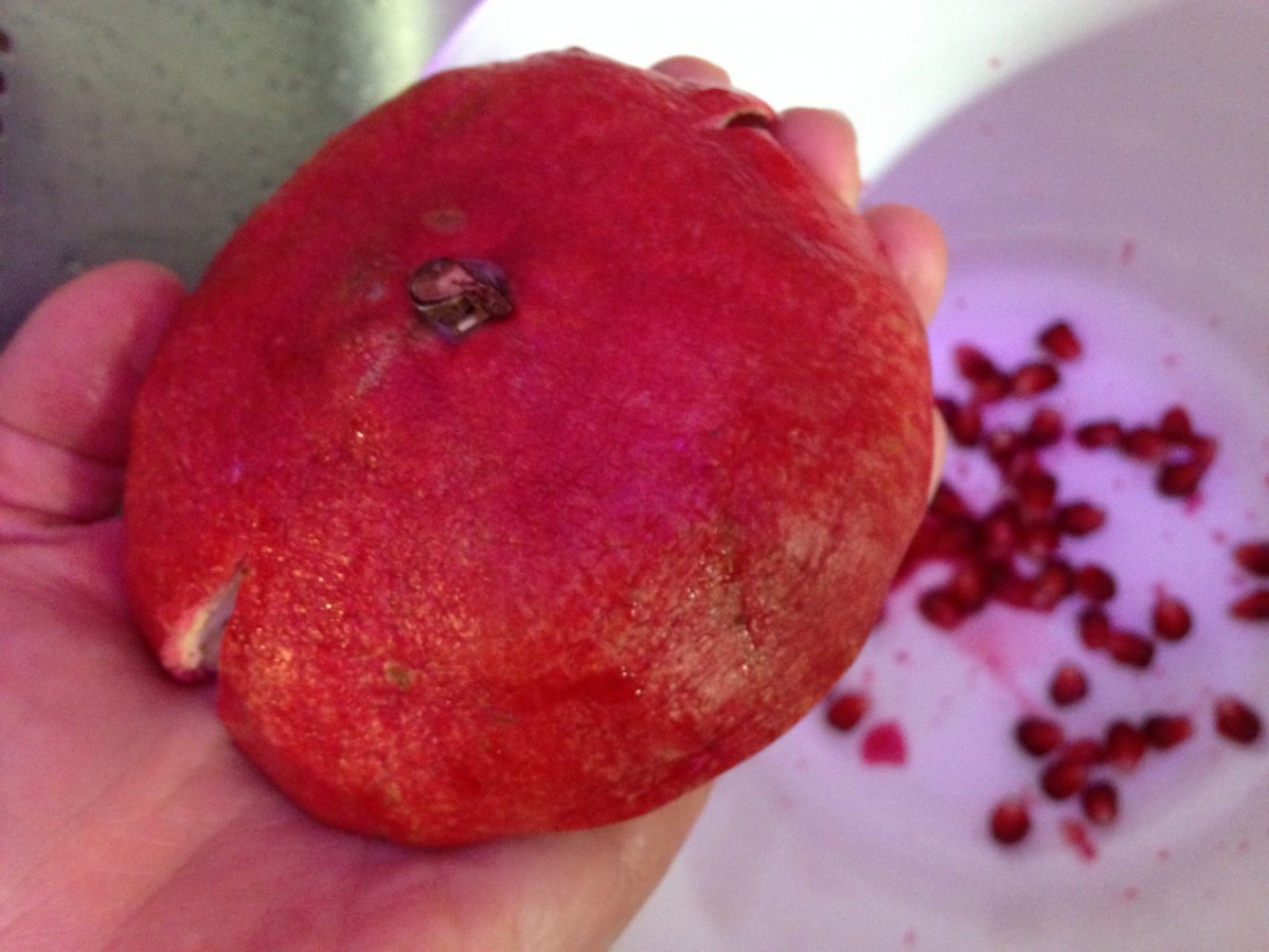Granatapfel über einer Schüssel umgedreht in den Handteller legen