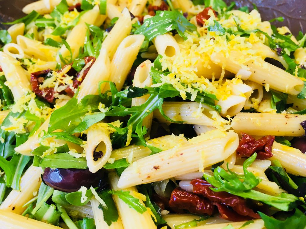 Italienischer Nudelsalat mit Tomaten, Oliven, Rucola und Pinienkernen