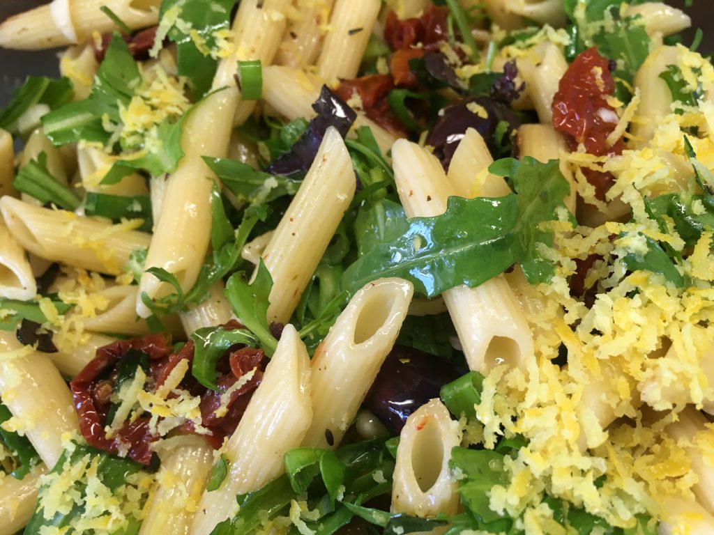 Italienischer Nudelsalat mit Tomaten, Oliven, Rucola und Pinienkernen